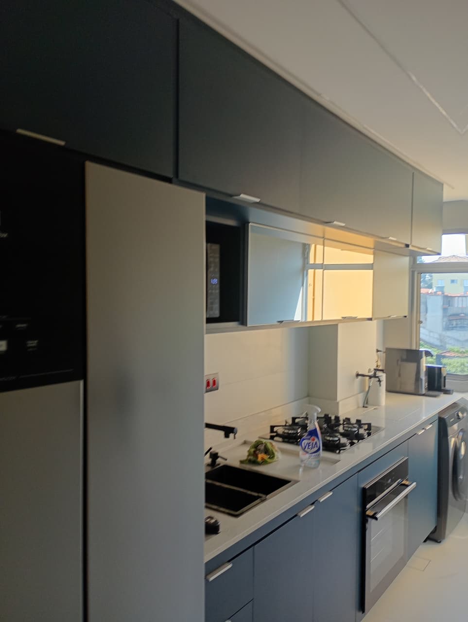 Vista da cozinha azul com nicho para micro-ondas e armários