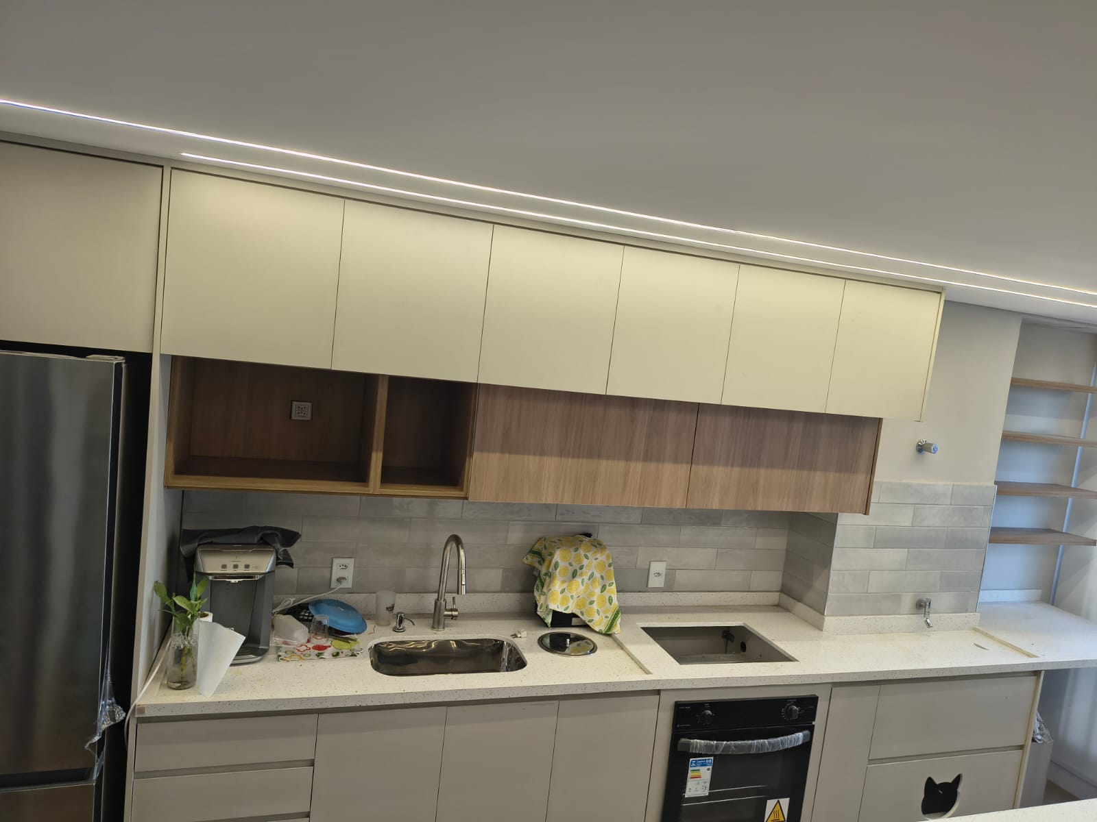 Cozinha planejada em tons claros com armários superiores e detalhes em madeira