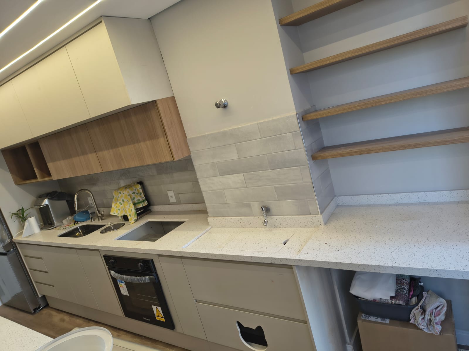 Detalhe da cozinha clara com prateleiras em madeira e módulos inferiores